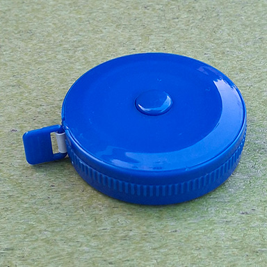 This is a tape measurer that has a cylindrical cover. It's a very simply shaped object that has a couple of details around it. 